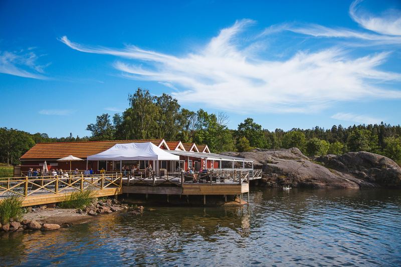 Waterside restaurant terrace with white tents by the rocks on Grinda