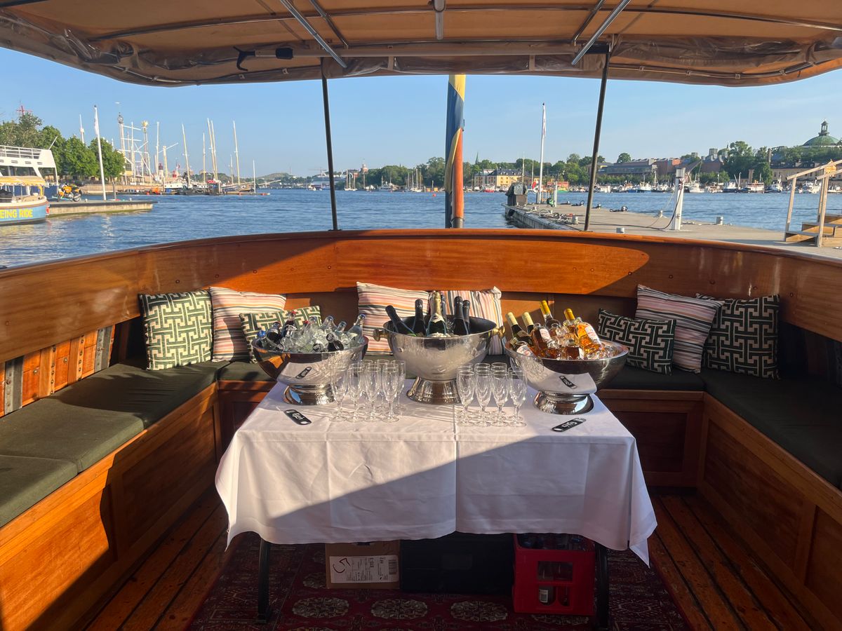 Champagne on ice and glasses set on the wooden aft deck of the classic boat Sara for a champagne boat tour in Stockholm